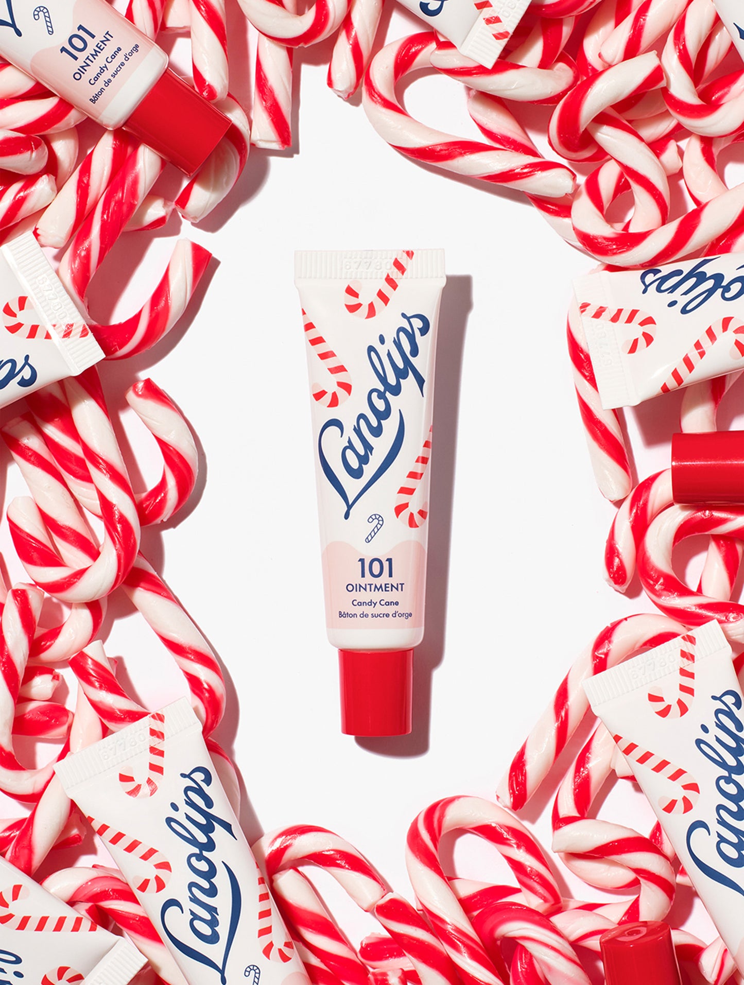 Lanolips 101 Ointment Multi-Balm Candy Cane tube surrounded by candy canes on a white background.